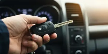 Mão segurando chave de carro com painel moderno ao fundo, simbolizando aprovação rápida de financiamento automotivo.