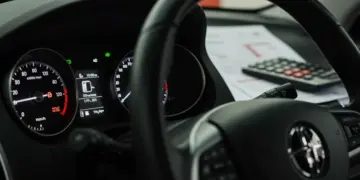 Painel de carro usado com documentos financeiros e calculadora, simbolizando a decisão de financiamento.